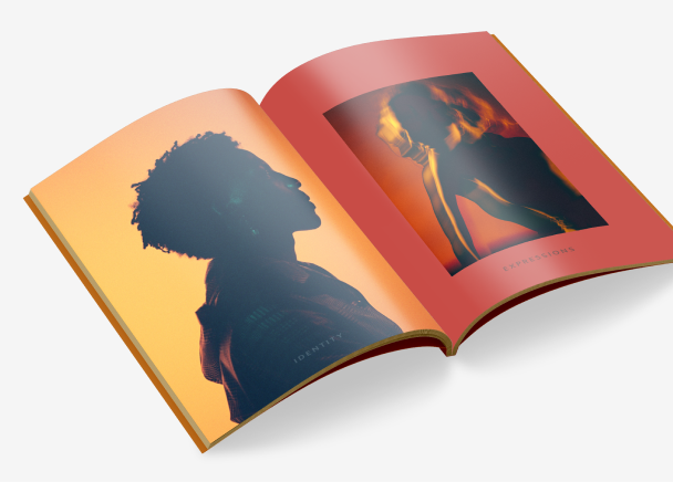 An open magazine featuring two pages with artistic, silhouette-style portraits. The left page displays a profile silhouette of a person against a warm yellow background, titled ‘Identity’, while the right page shows another silhouette of a person against a red-orange background, titled 'Expressions.'